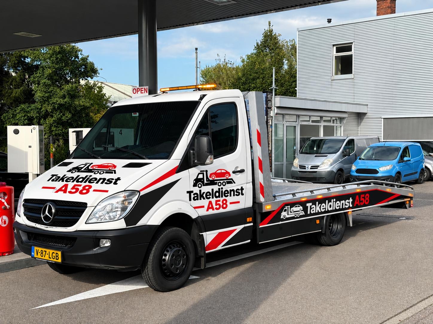 De witte takelwagen van Takeldienst A58 met rood-zwarte belettering